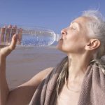 امرأة تشرب الماء بعد ممارسة التمارين الرياضية