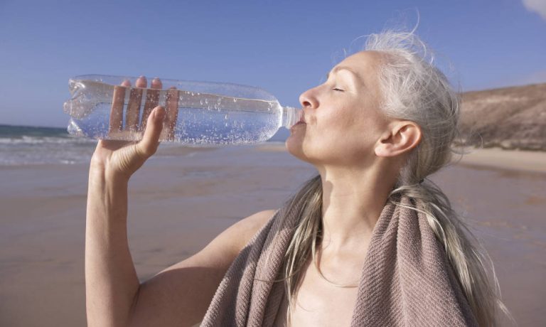 امرأة تشرب الماء بعد ممارسة التمارين الرياضية